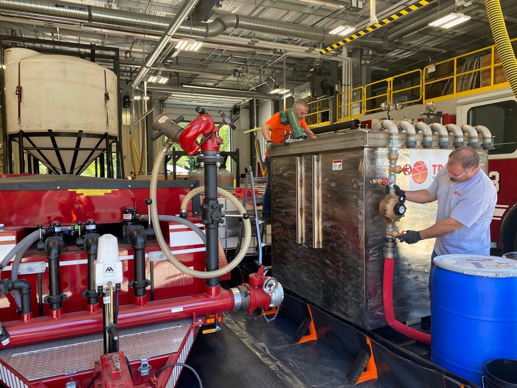 Greg Knight (middenboven) en Steve Pistoll (rechtsonder) controleren PerfluorAd terwijl het werkt om PFAS te verwijderen uit het spoelwater van brandweervoertuigen bij een brandweerkazerne in Connecticut.