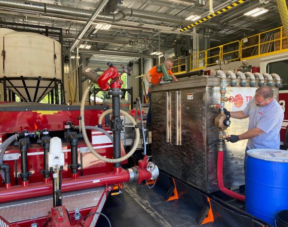 Greg Knight (canto superior) e Steve Pistoll (canto inferior direito) monitoram o sistema PerfluorAd para correção de PFAS em um corpo de bombeiros em Connecticut.