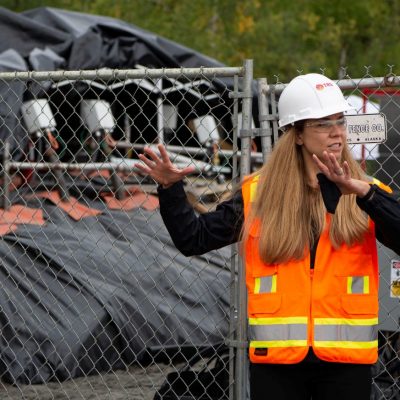 Emily Crownover, Managing Principal Engineer, leads a tour at Eielson Air Force Base in Fairbanks, Alaska, where TRS is using thermal remediation on PFAS containing ex situ soil stockpiles (pictured in the background).