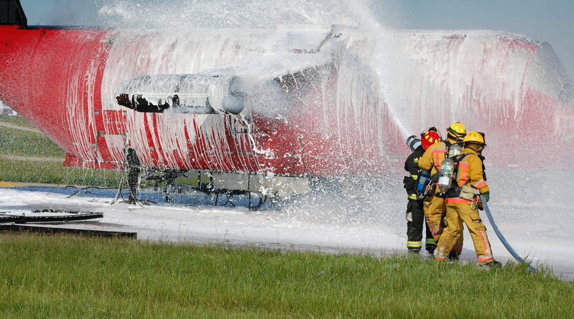 Os bombeiros pulverizam um avião com espuma de combate a incêndios.