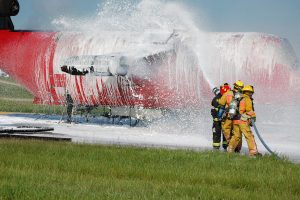 Brandweerlieden spuiten een vliegtuig met blusschuim.
